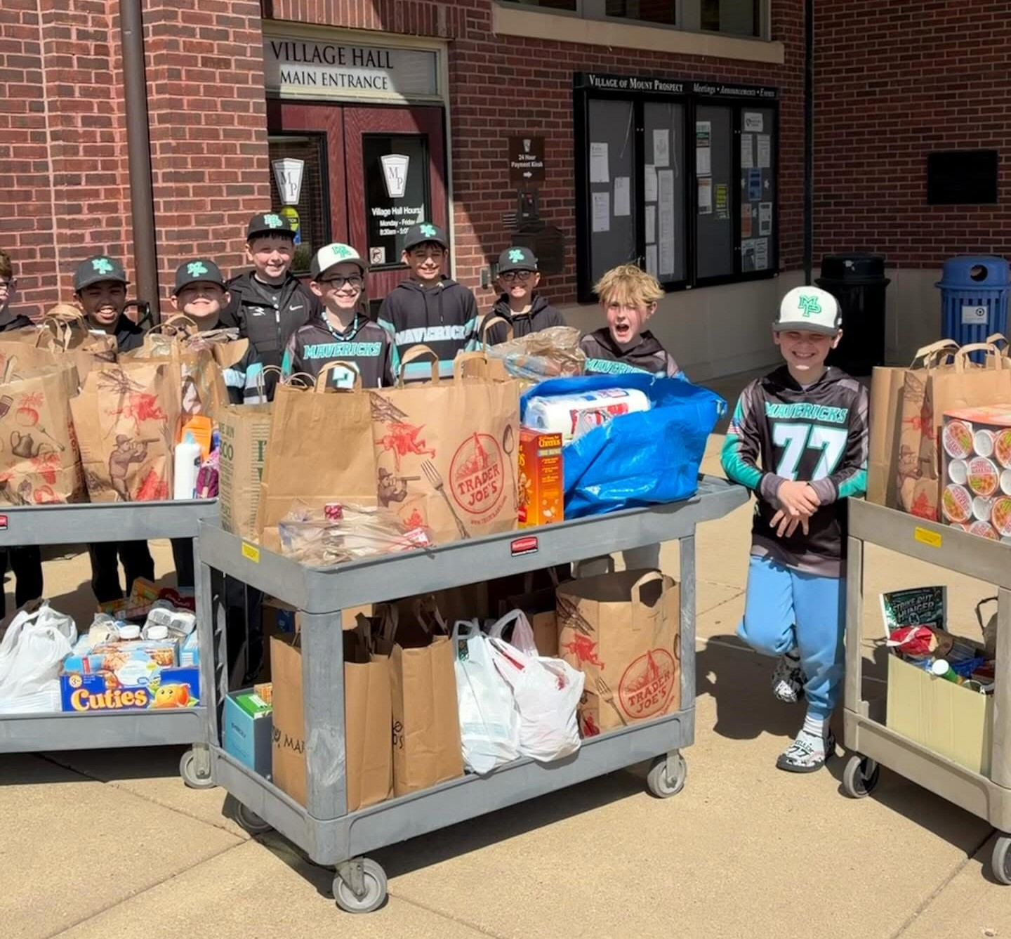 Mavericks players volunteering at a community food drive, carrying grocery bags