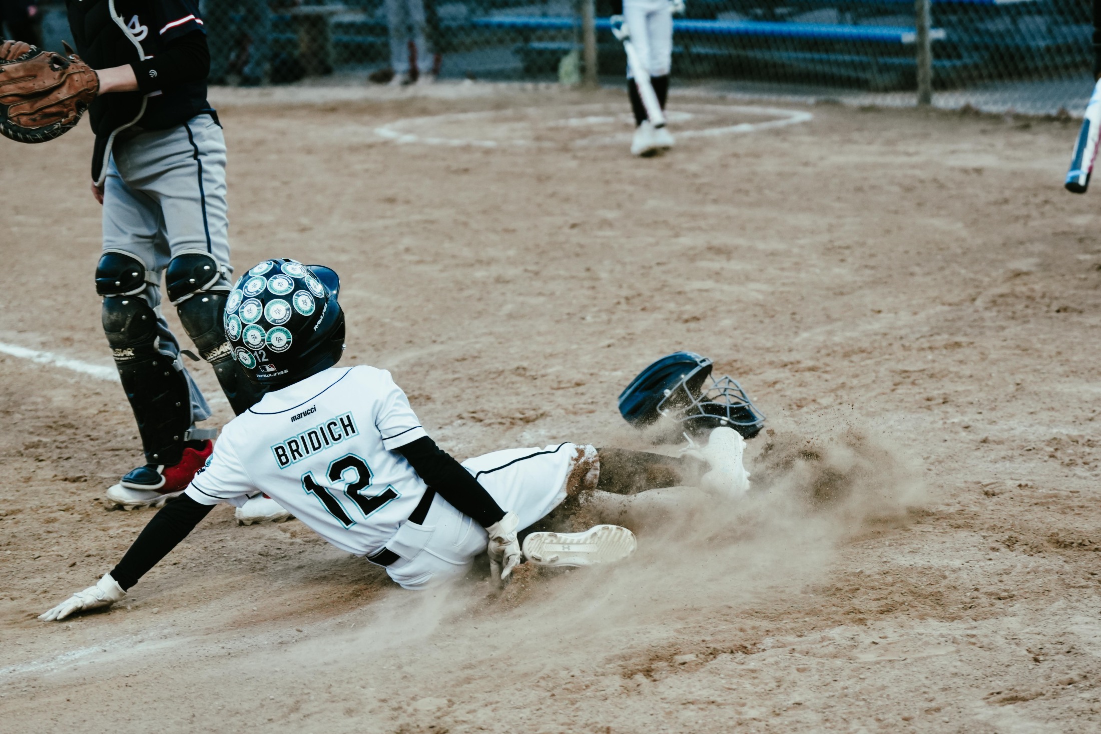 Mavericks player sliding into home plate, dust flying