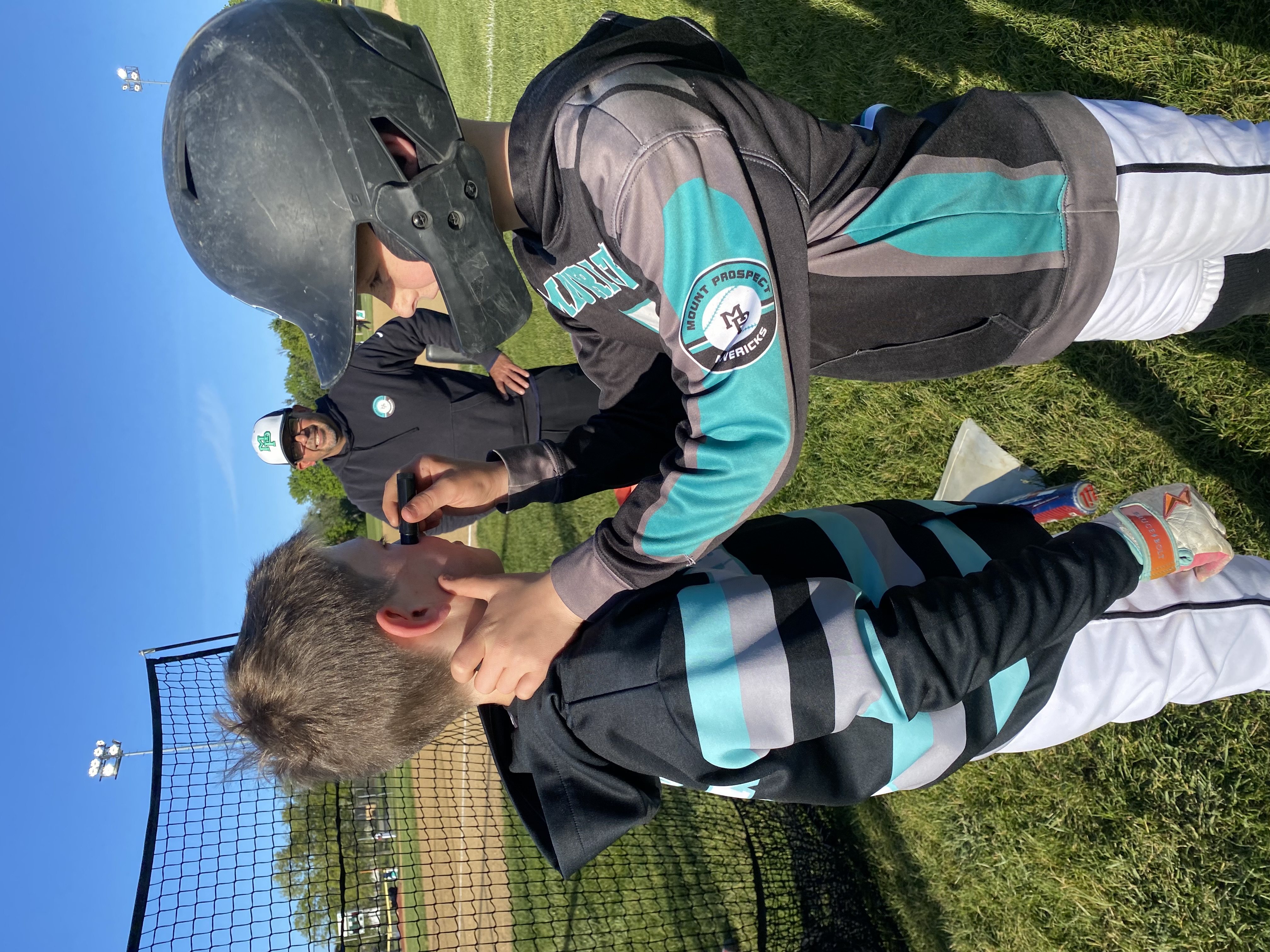 Coach helping a young Mavs player with his helmet