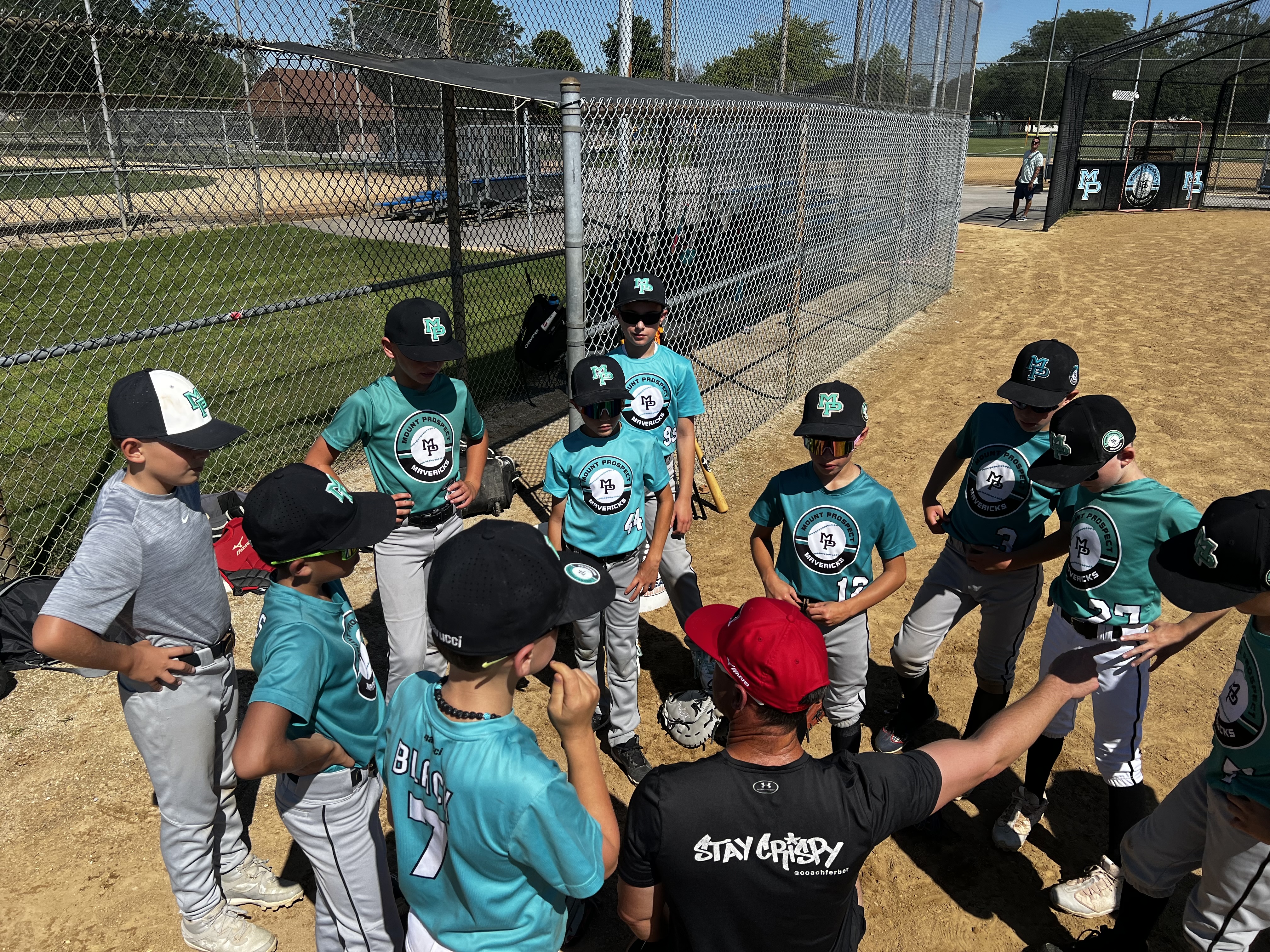 Young Mavs in practice gear gathered around coach