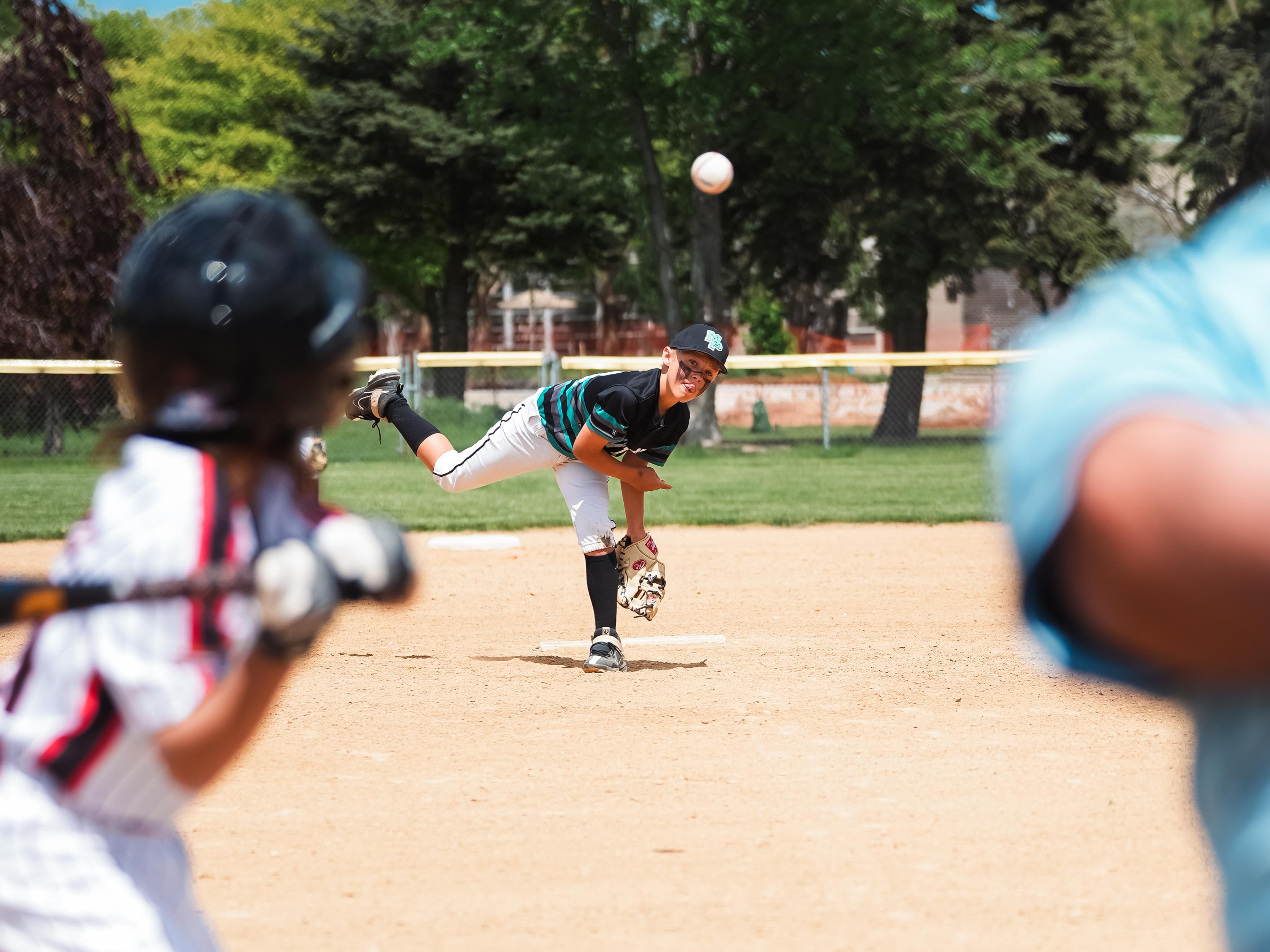 Mavericks pitcher mid-throw with the ball mid-flight toward home plate
